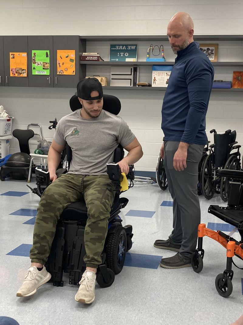 Man sitting in a wheelchair with man standing in a lab